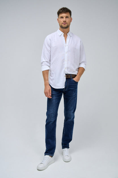 Man wearing a white shirt, blue jeans, and white sneakers on a gray background