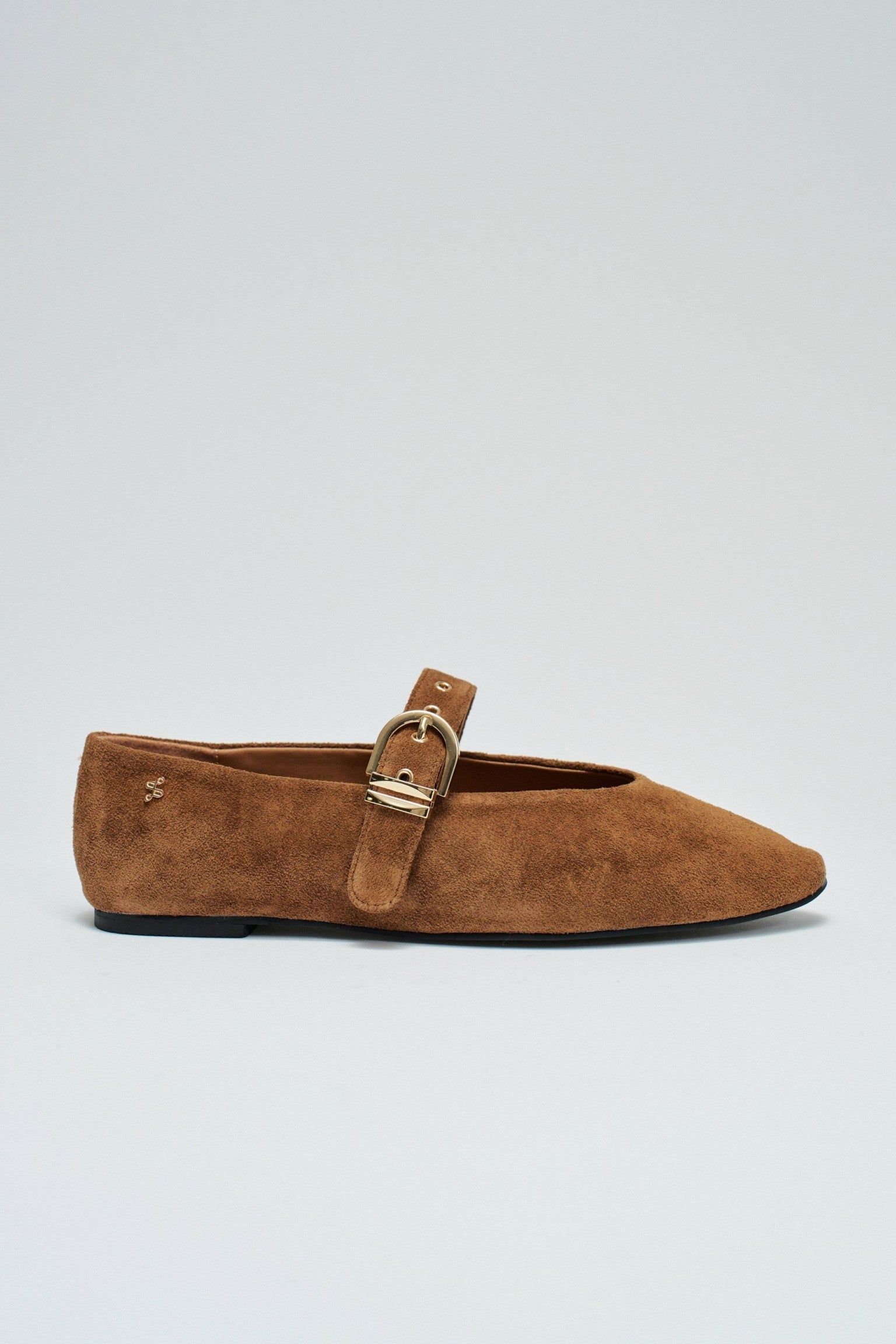 A single brown suede flat shoe with a pointed toe and a gold-tone buckle strap, shown in profile against a light gray background.