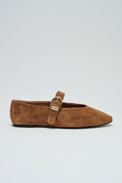 A single brown suede flat shoe with a pointed toe and a gold-tone buckle strap, shown in profile against a light gray background.