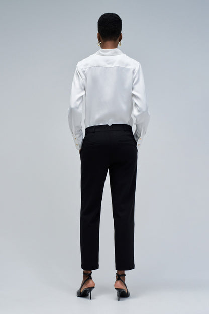 Person wearing a white shirt and black pants on a gray background