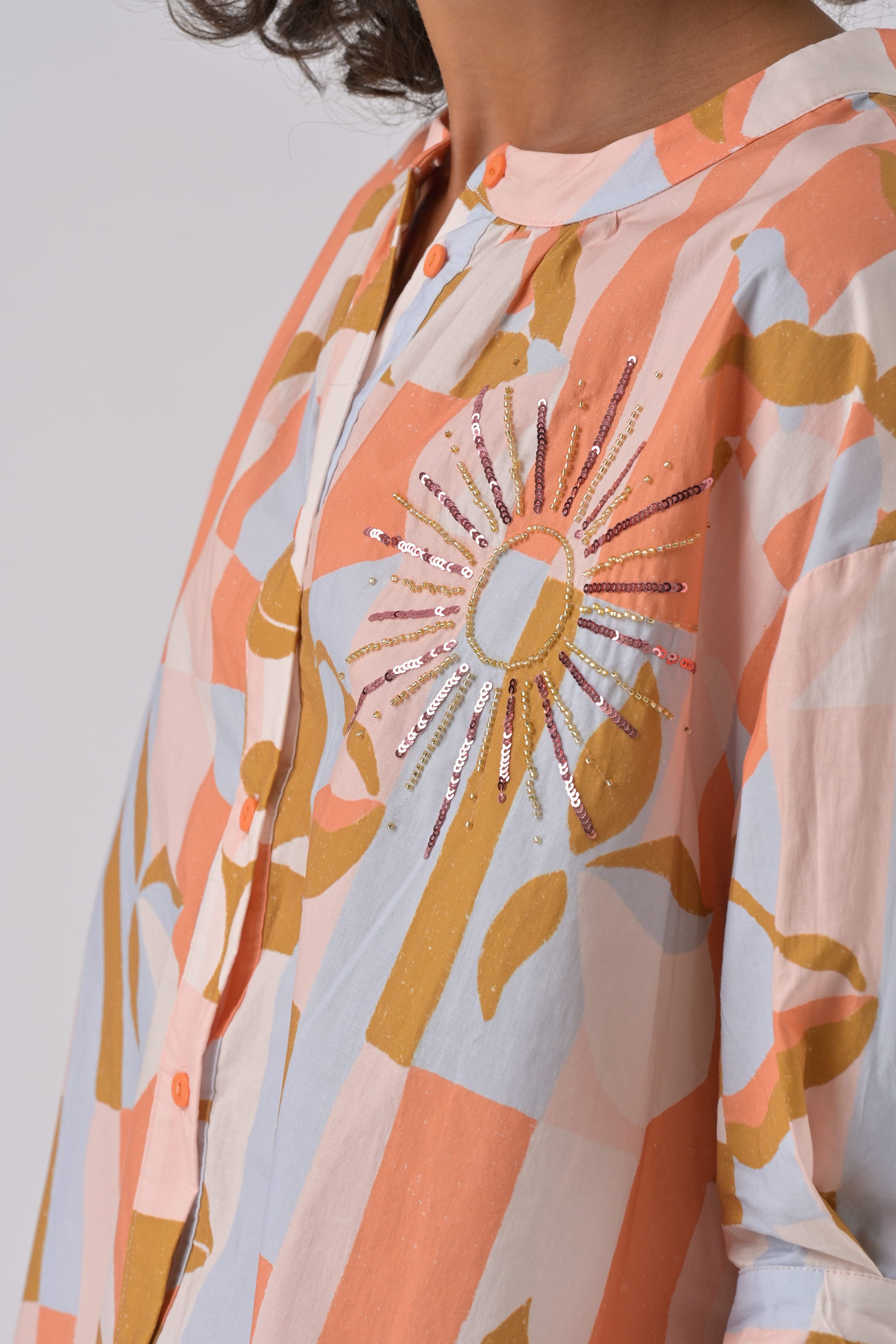 Close-up of a person wearing a patterned outfit with a prominent sun design.