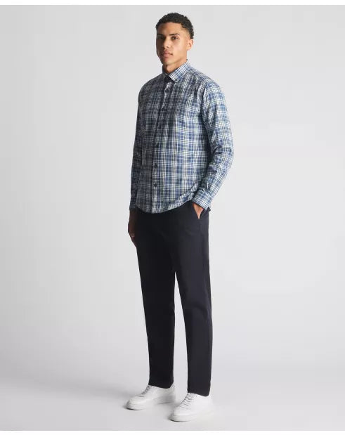 Man wearing a blue plaid shirt and black pants on a white background