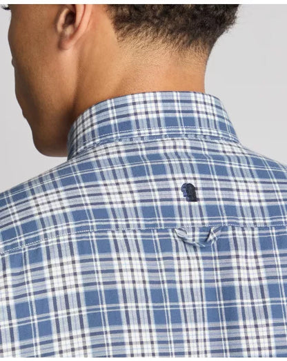 Close-up of a person wearing a blue and white checkered shirt with a brand logo on a gray background