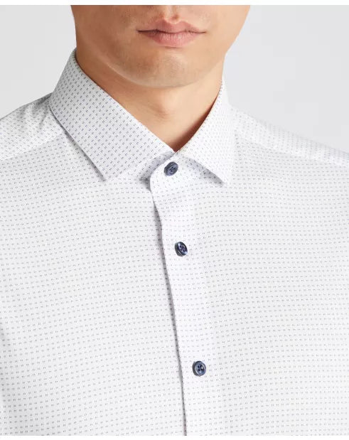 Close-up of a white shirt with a subtle pattern worn by a person.