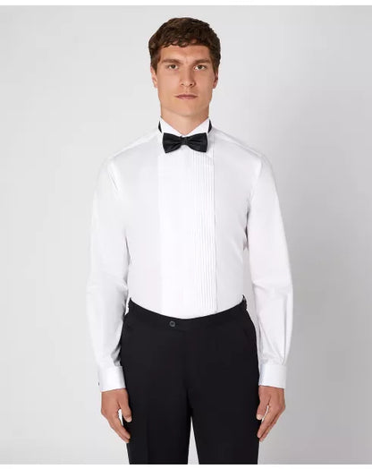 Man wearing a white dress shirt with a black bow tie and black pants on a light gray background