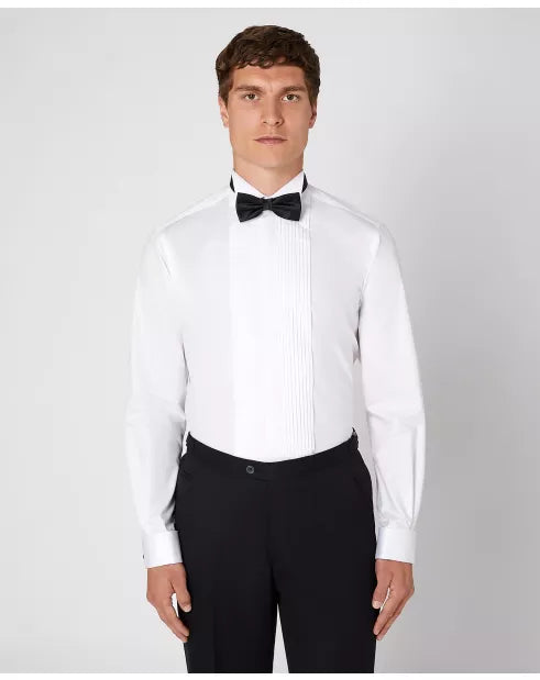 Man wearing a white dress shirt with a black bow tie and black pants on a light gray background