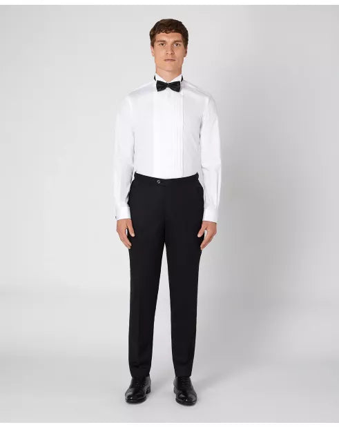 Man wearing a white dress shirt with a black bow tie and black pants on a white background