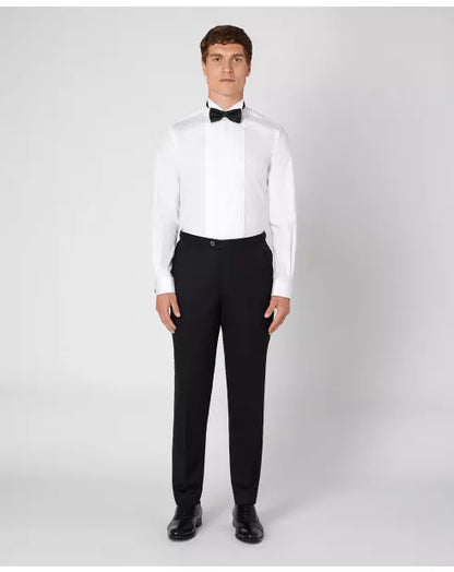 Man wearing a white dress shirt with a black bow tie and black pants on a white background
