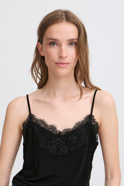 Woman wearing a black lace-trimmed top against a plain background