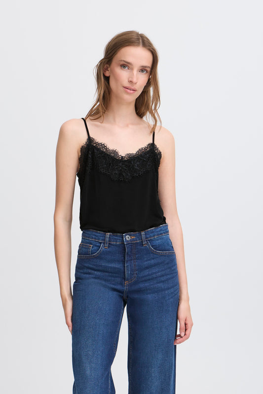 Woman wearing a black lace camisole and blue jeans on a white background