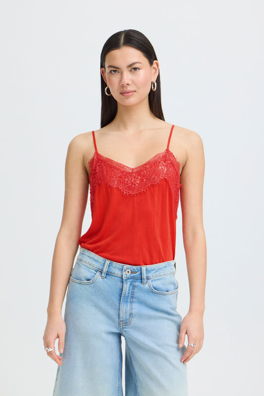 Woman wearing a red lace-trimmed top and light blue jeans on a white background