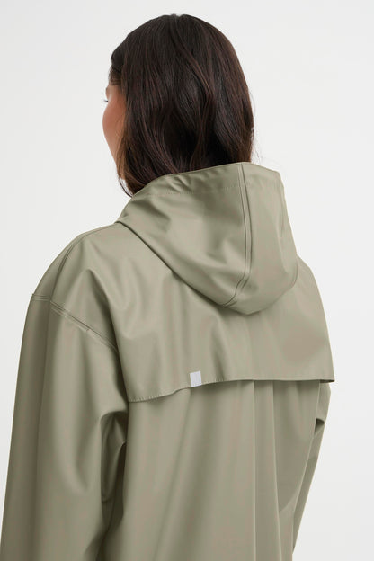 Person wearing a light green raincoat on a white background