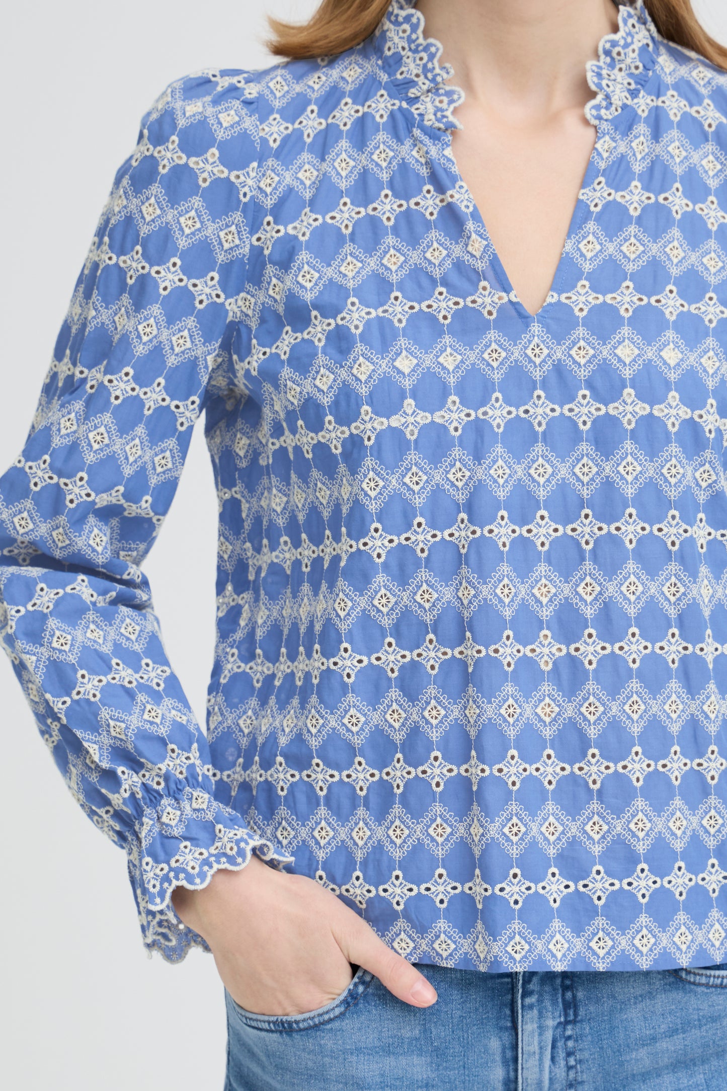 Blue patterned blouse worn by a person with a white background