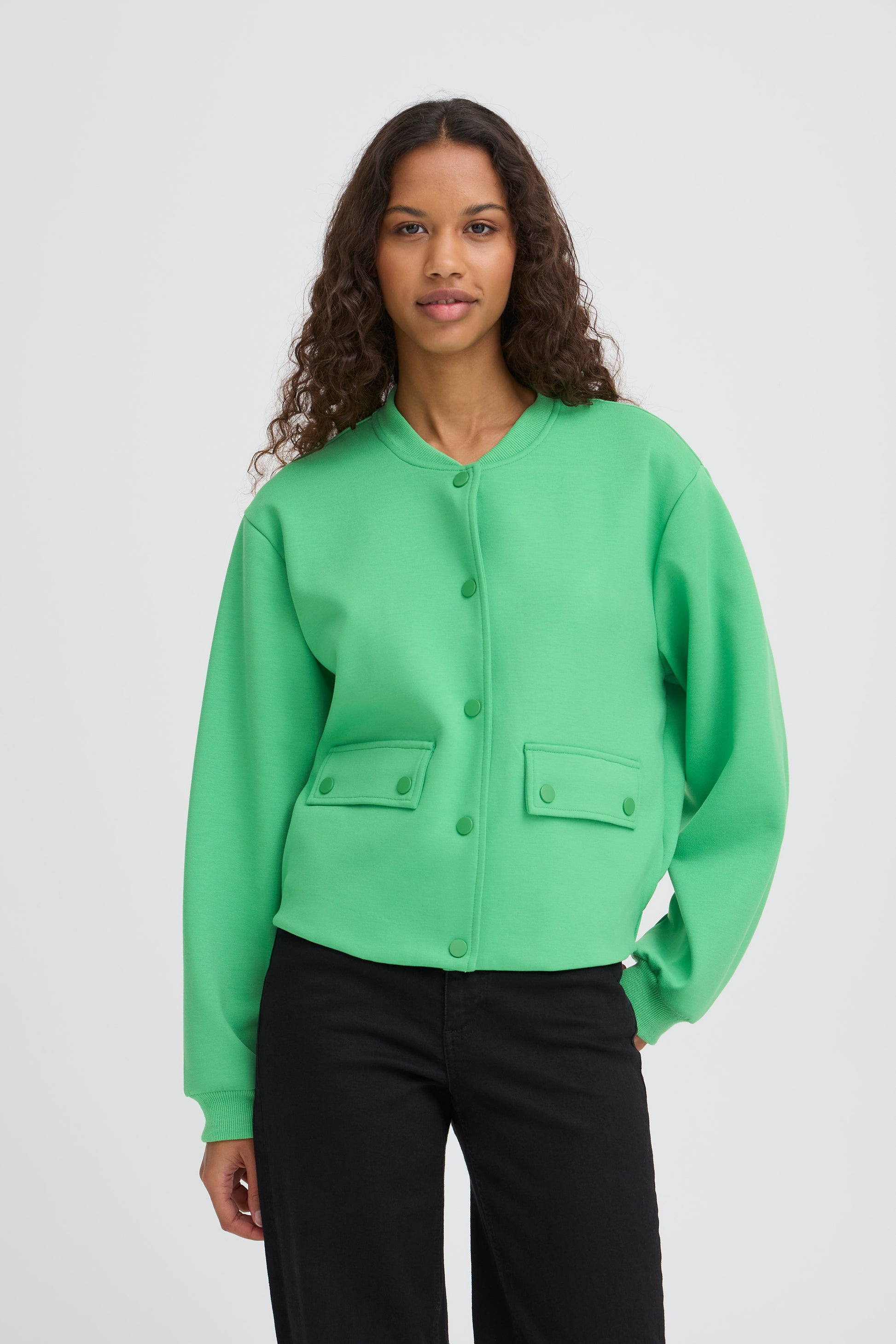 Woman wearing a light green jacket with black pants on a white background
