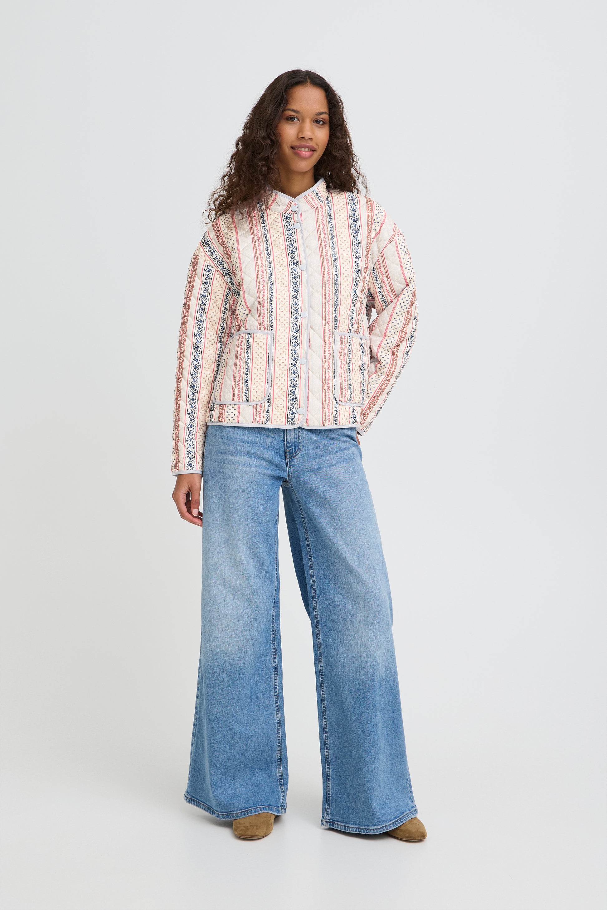 Woman wearing a striped shirt and blue jeans on a white background