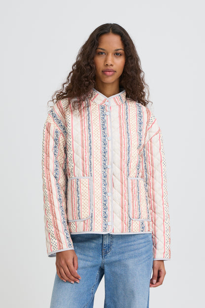 Woman wearing a patterned shirt and jeans on a plain background