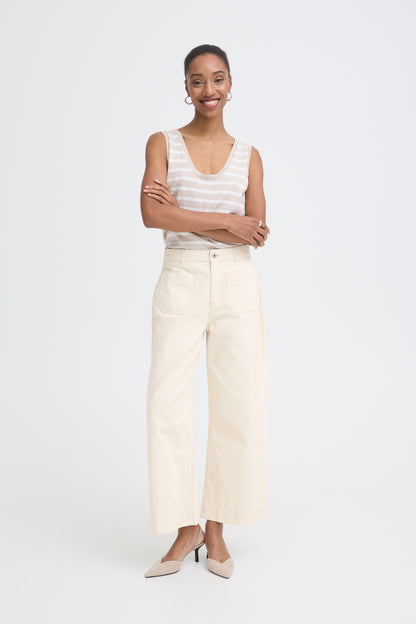 Woman wearing a white sleeveless top and beige pants on a white background