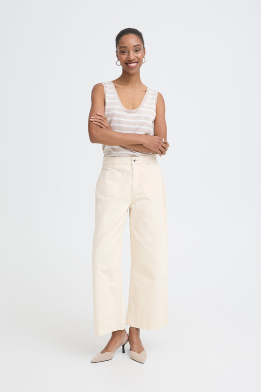 Woman wearing a white sleeveless top and beige pants on a white background