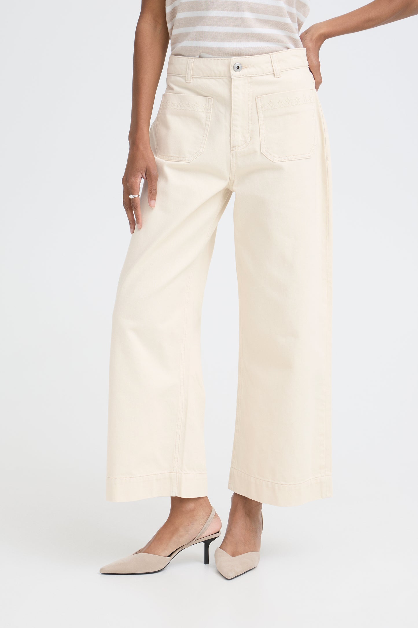 Person wearing cream-colored wide-leg pants on a white background