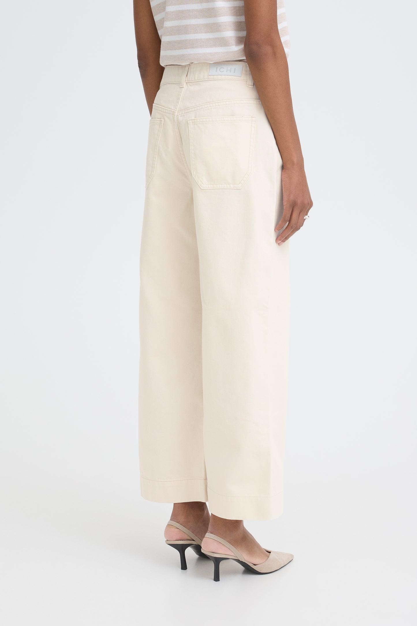 Person wearing white wide-leg pants on a white background