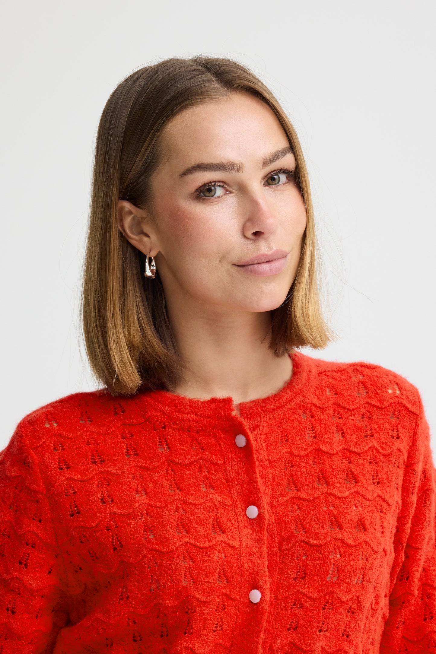 Woman wearing a red textured cardigan against a light background