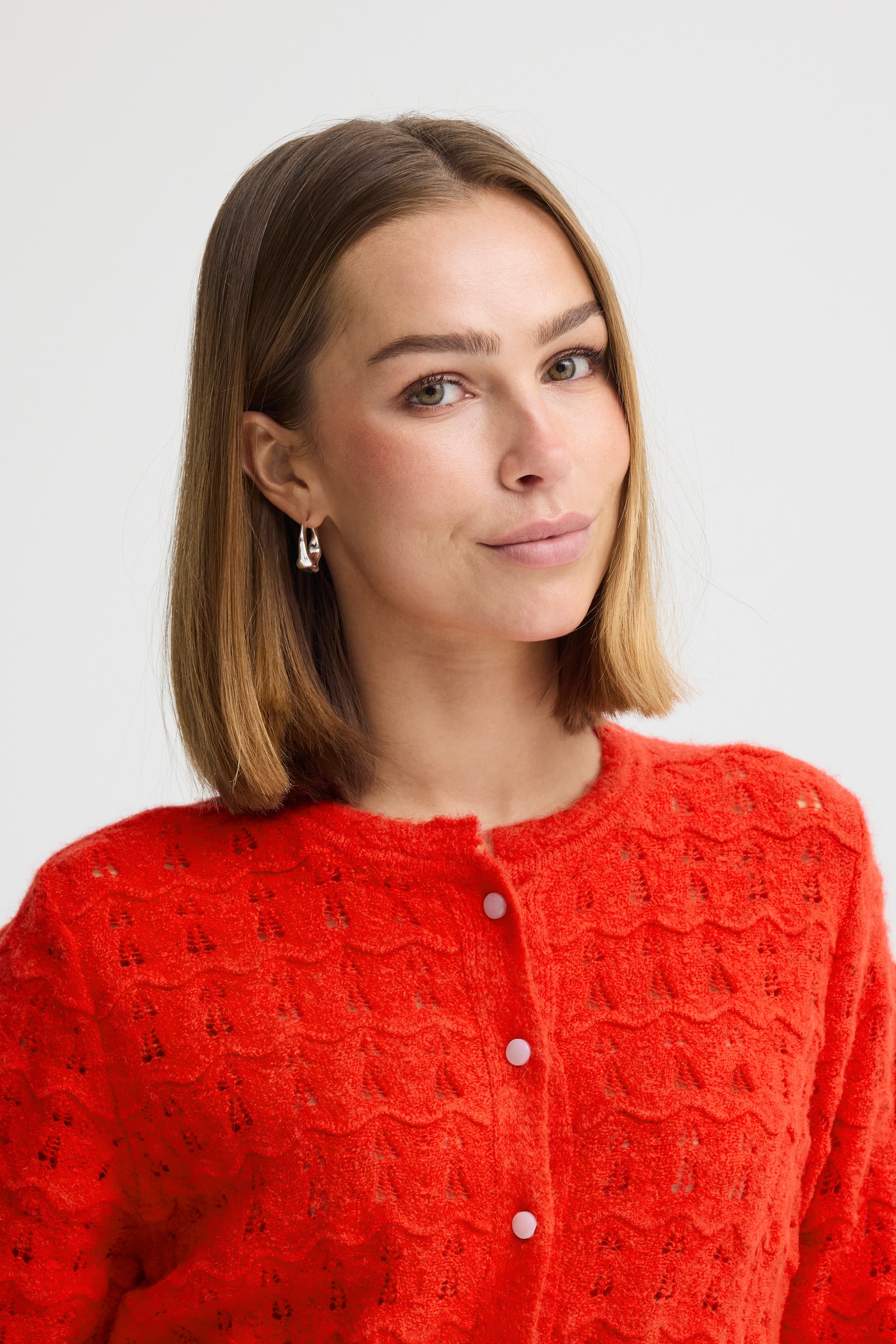 Woman wearing a red textured cardigan against a light background