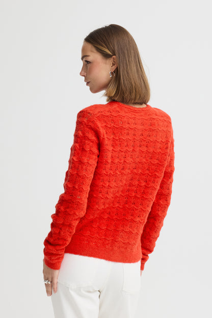 Person wearing a red textured sweater on a white background