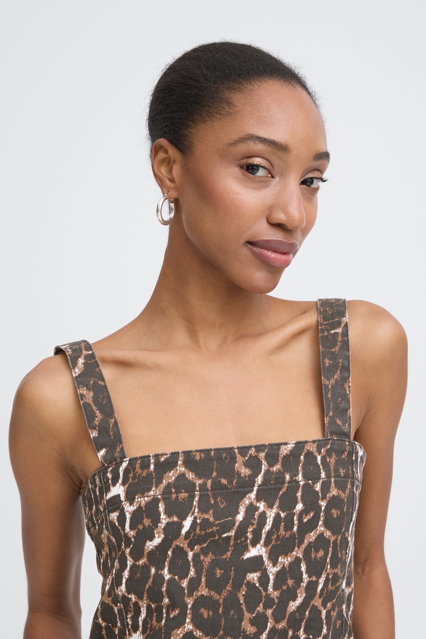 Woman wearing a leopard print dress against a plain background