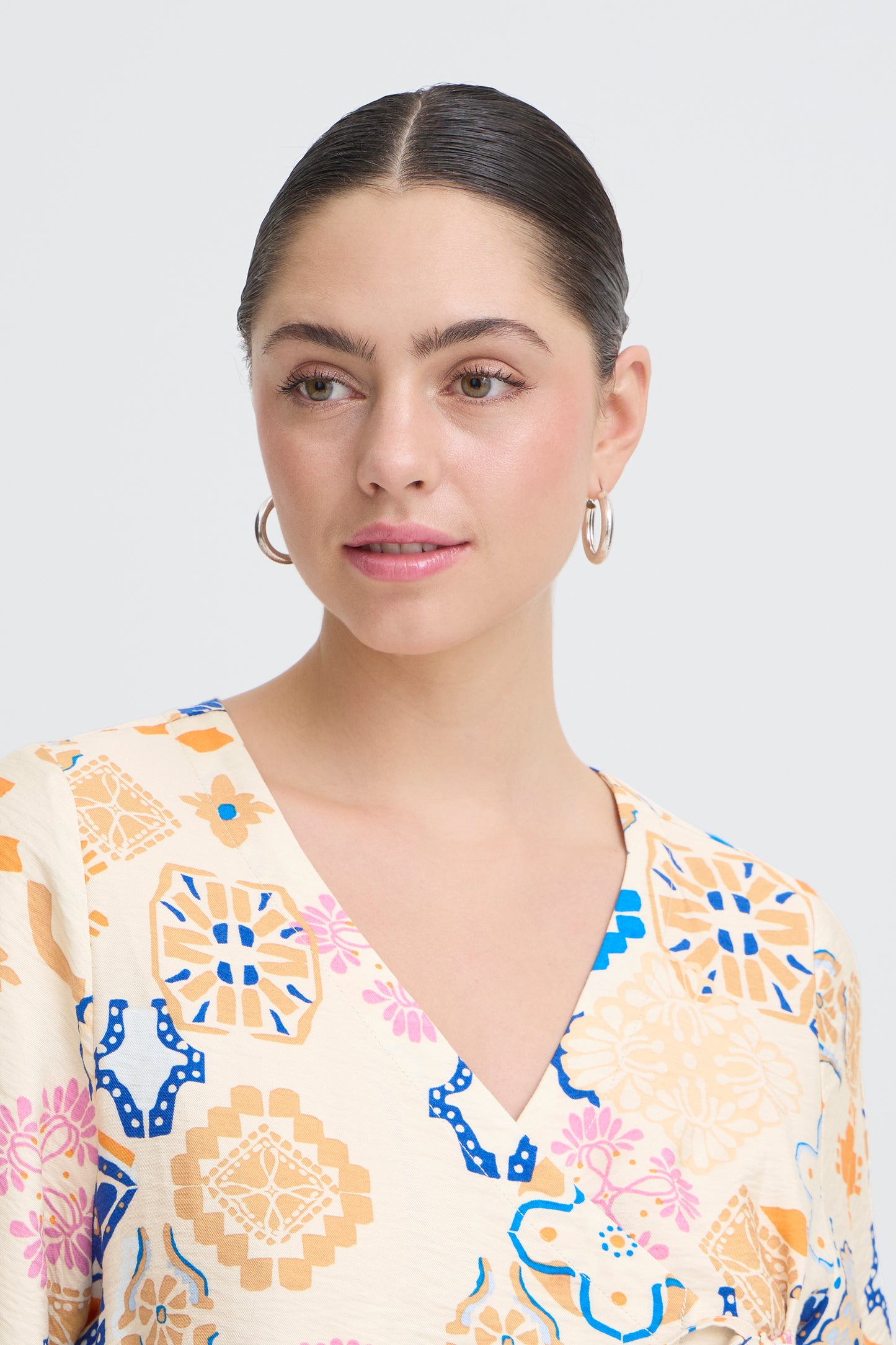 Woman wearing a patterned top against a plain background