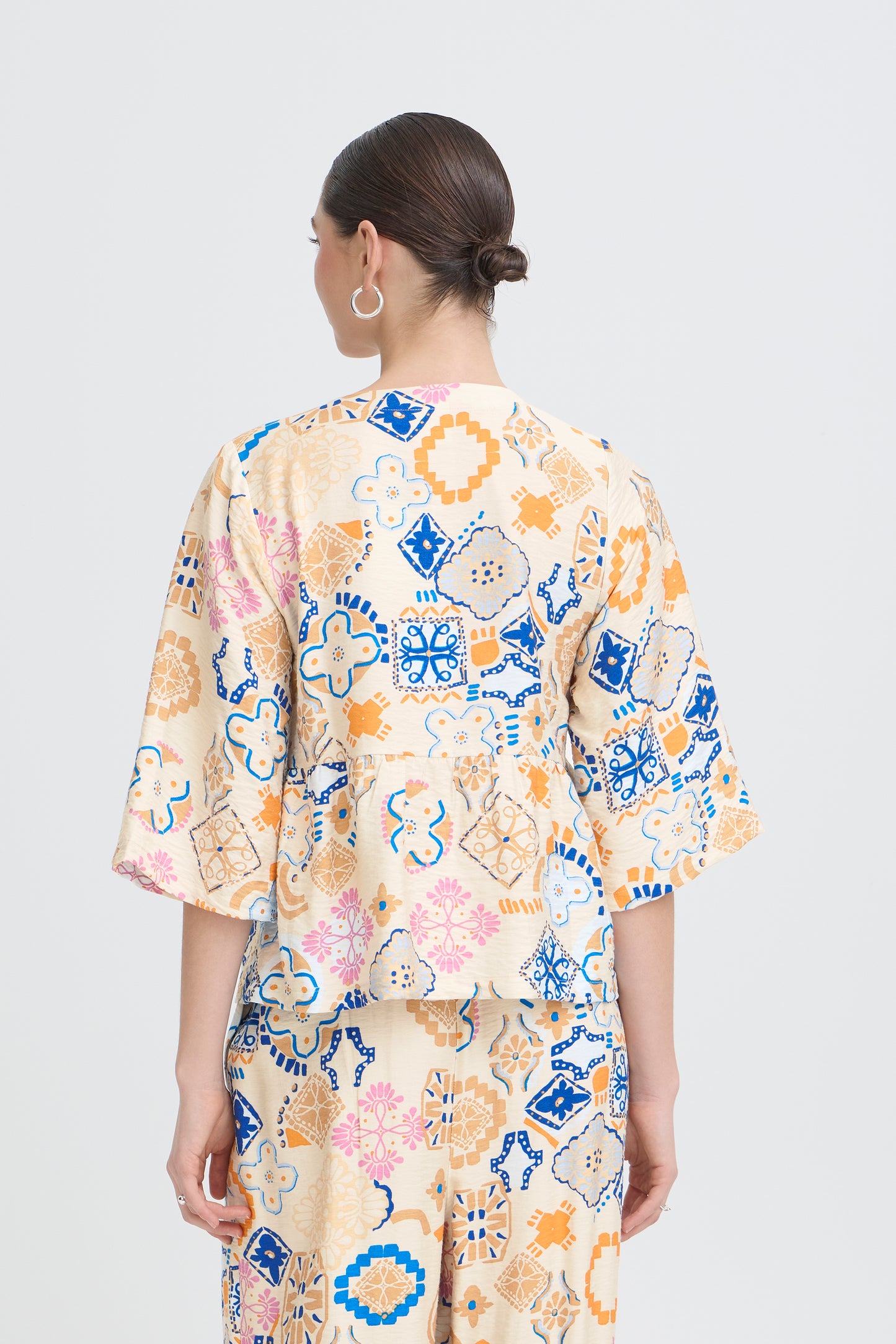 Woman wearing a floral kimono-style outfit on a plain background
