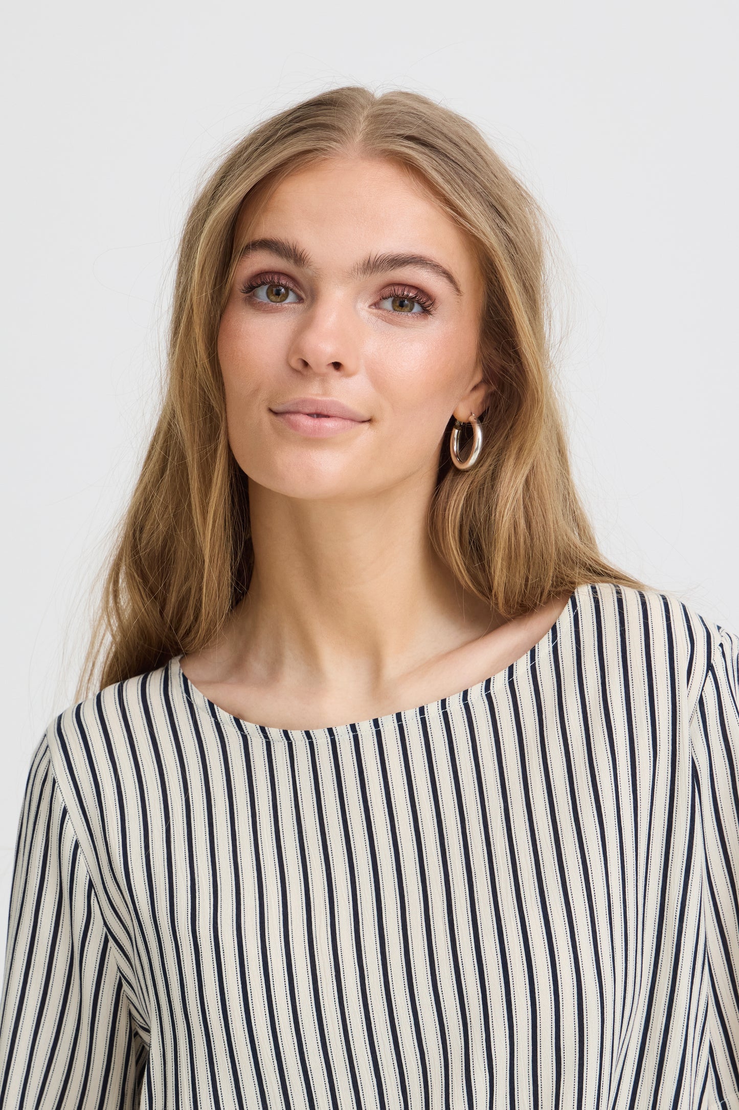 Woman wearing a black and white striped shirt against a plain background