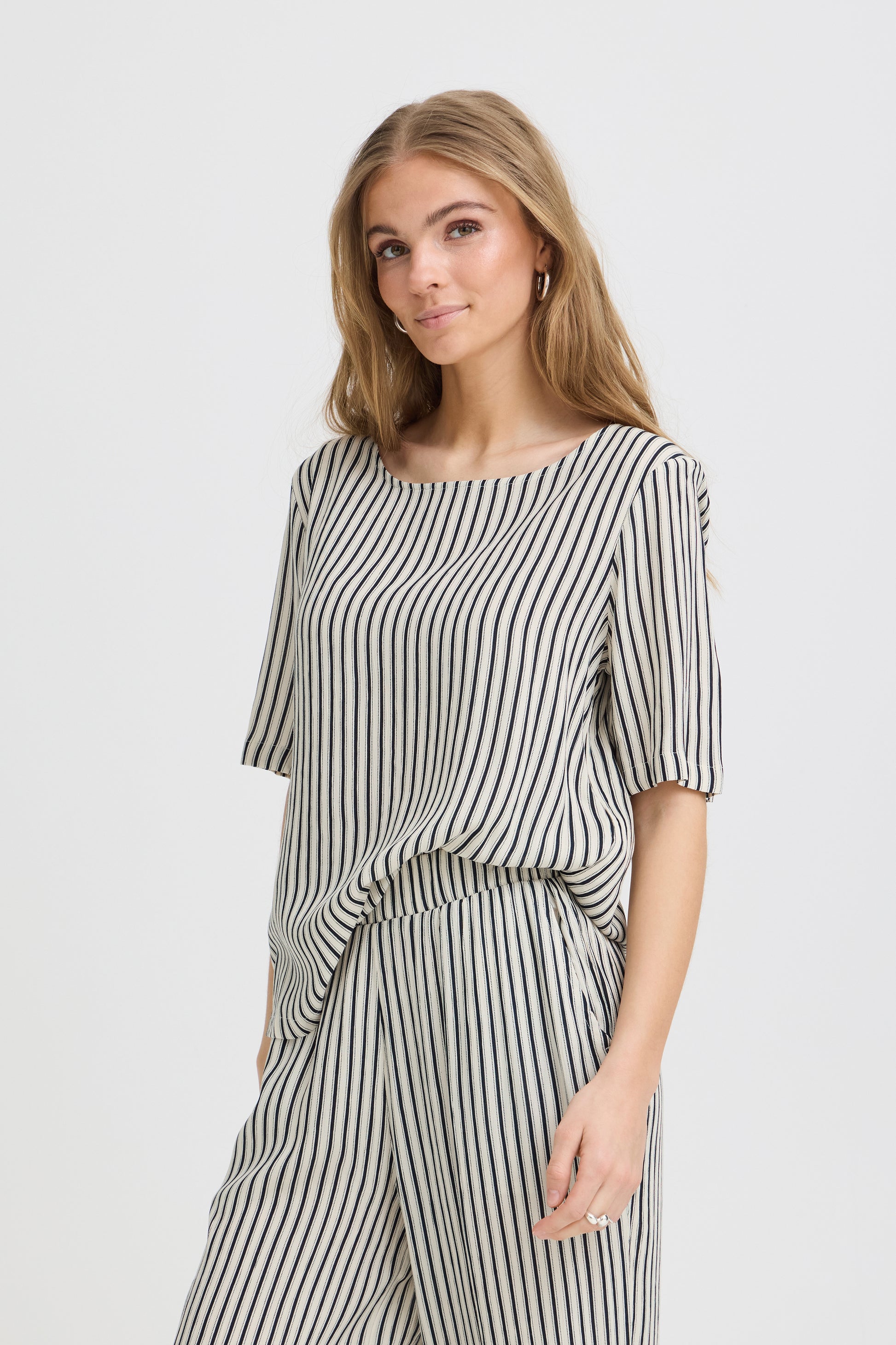 Woman wearing a black and white striped outfit on a plain background