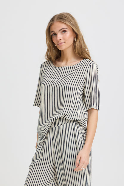 Woman wearing a black and white striped outfit on a plain background