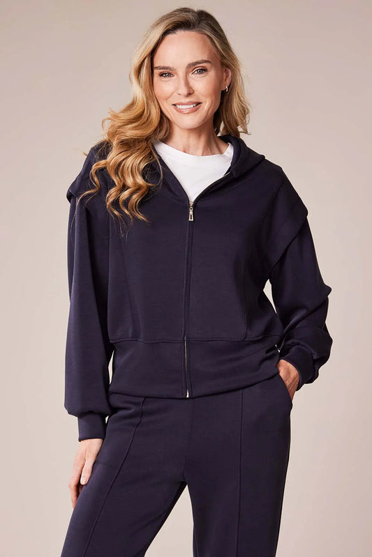 Woman wearing a navy blue tracksuit against a beige background