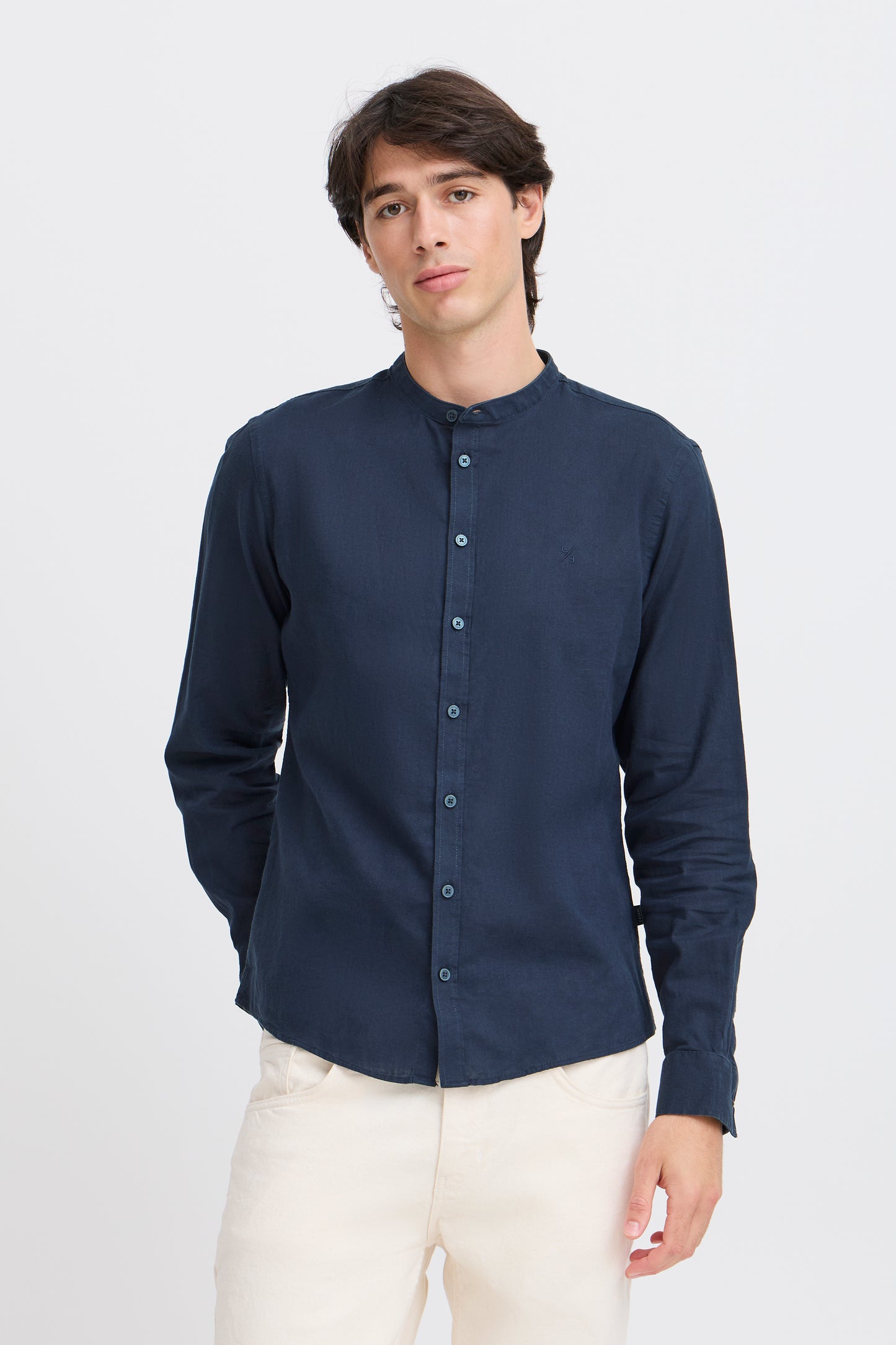 Man wearing a navy button-up shirt with a stand-up collar on a white background