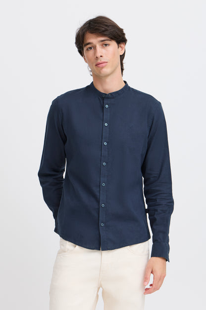 Man wearing a navy button-up shirt with a stand-up collar on a white background