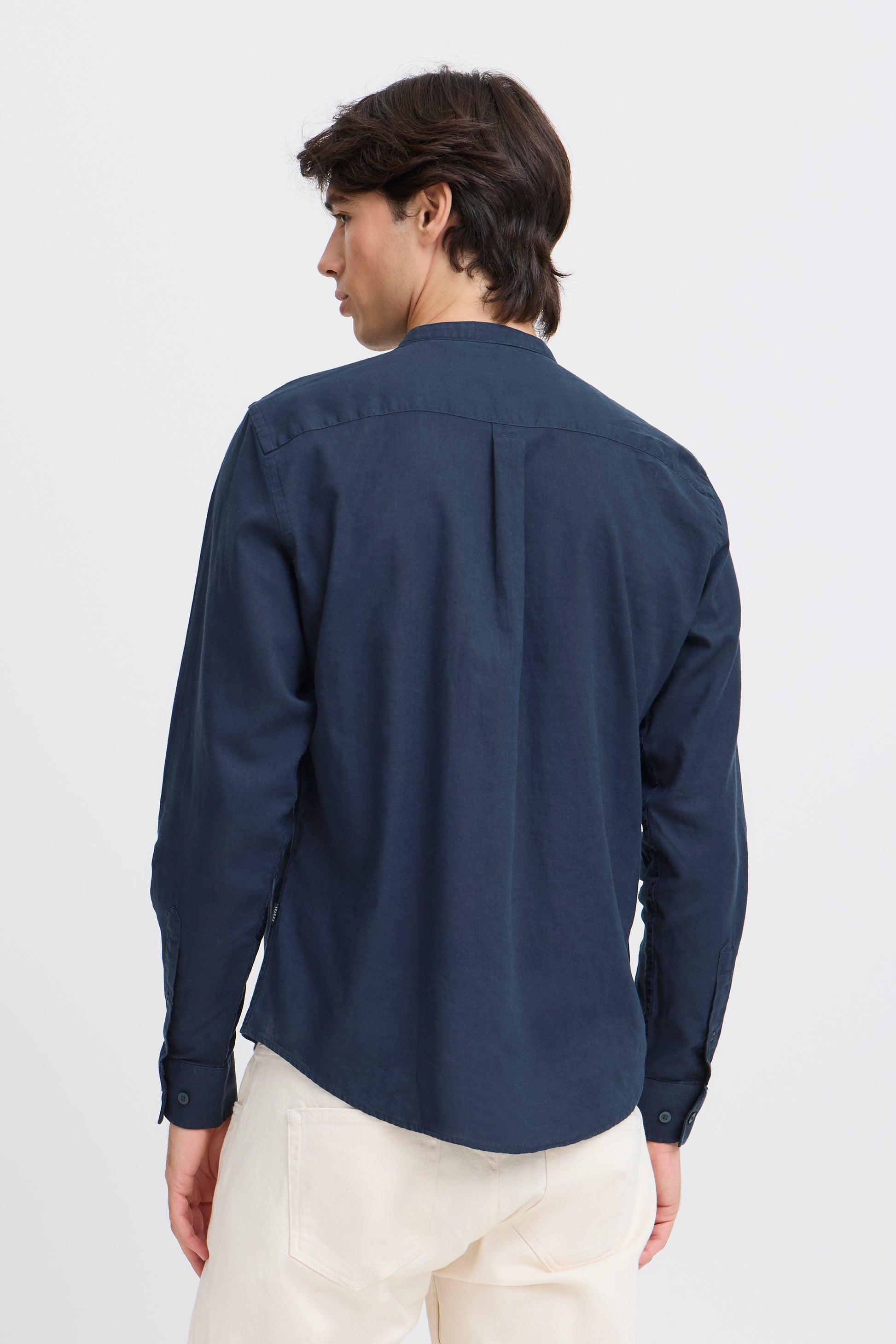 Person wearing a navy blue shirt and white pants on a light gray background