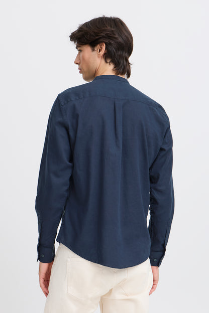 Person wearing a navy blue shirt and white pants on a light gray background