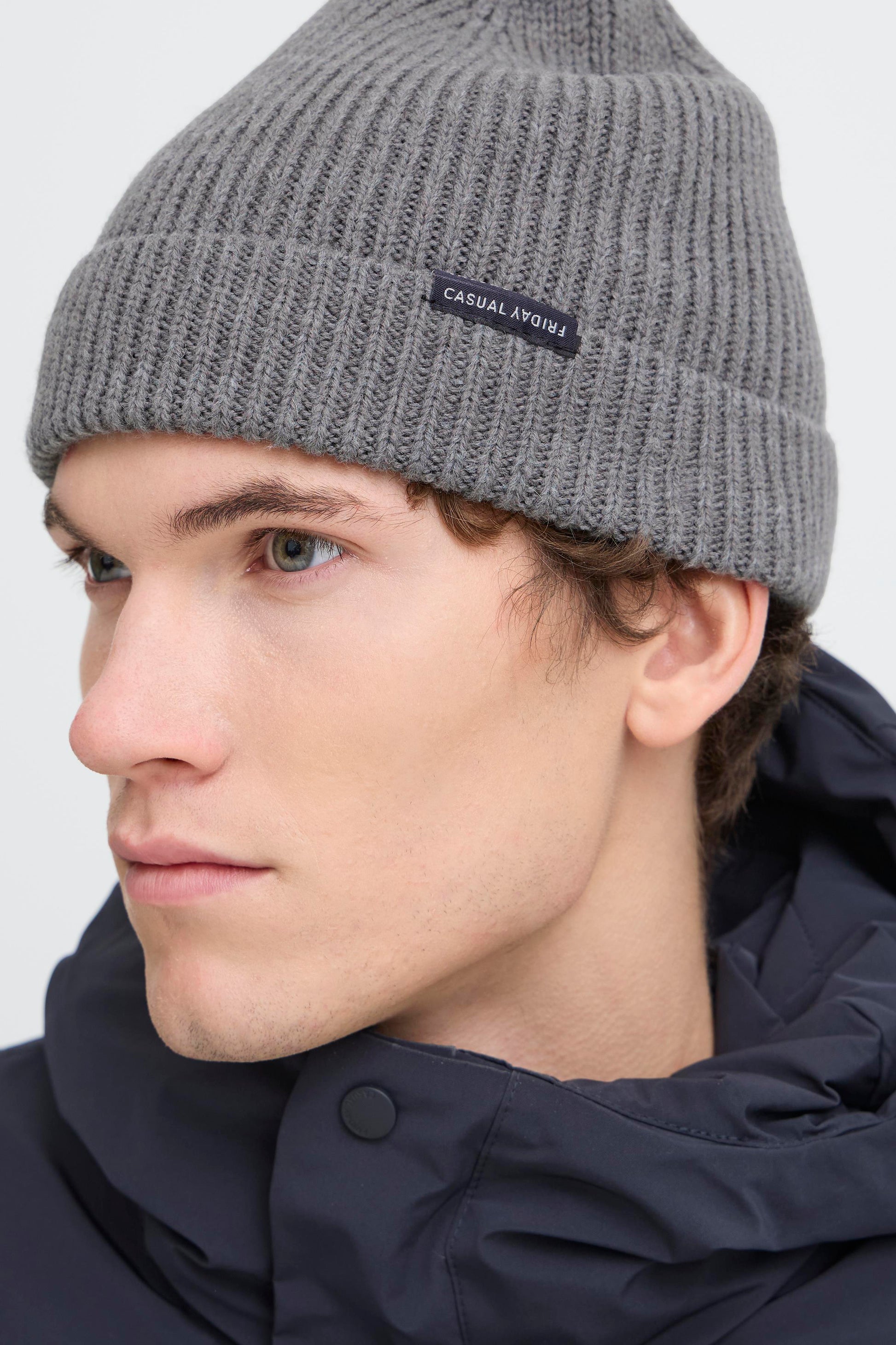 A close-up of a man wearing a gray ribbed knit beanie with a small black brand label that reads 'Casual Lifestyle'.