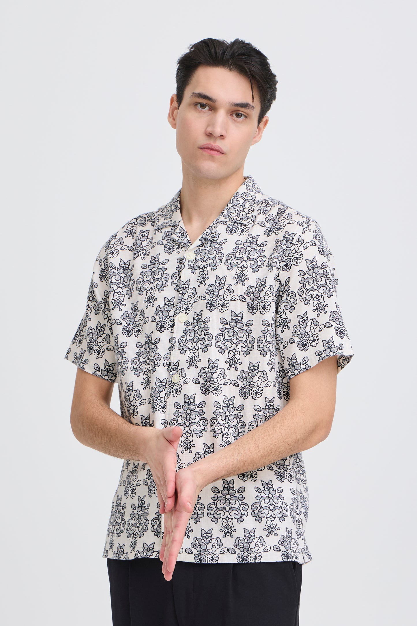 Man wearing a patterned shirt on a plain background