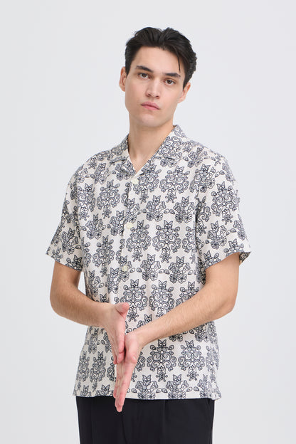 Man wearing a patterned shirt on a plain background
