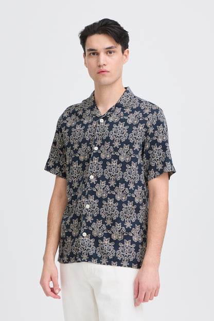 Man wearing a navy floral patterned shirt on a white background