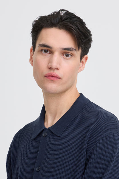 Man wearing a dark blue textured shirt against a white background