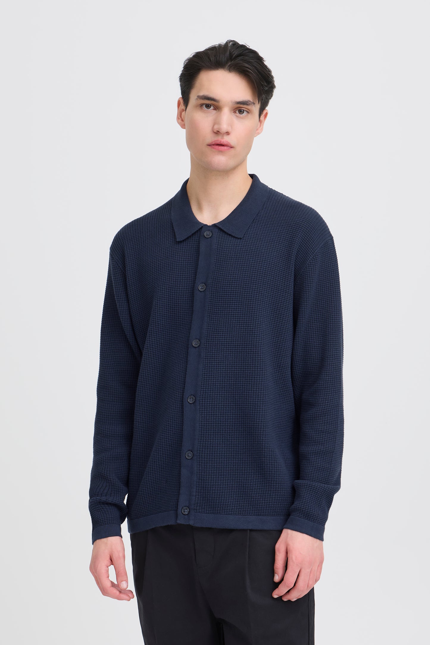 Man wearing a navy blue textured shirt on a white background