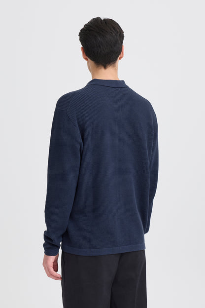 Person wearing a dark blue long-sleeve shirt on a light gray background