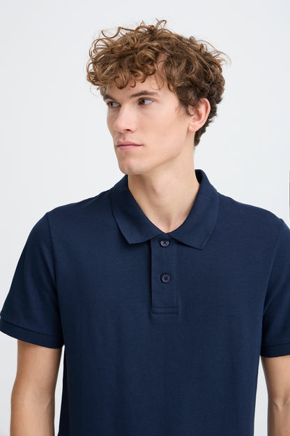Man wearing a navy blue polo shirt against a white background