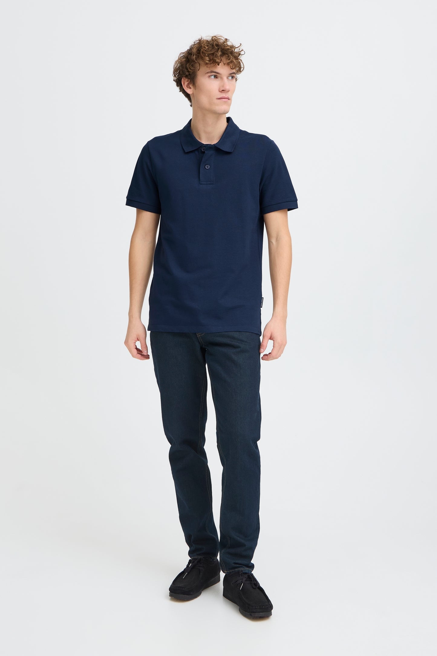 Person wearing a navy polo shirt and pants on a white background