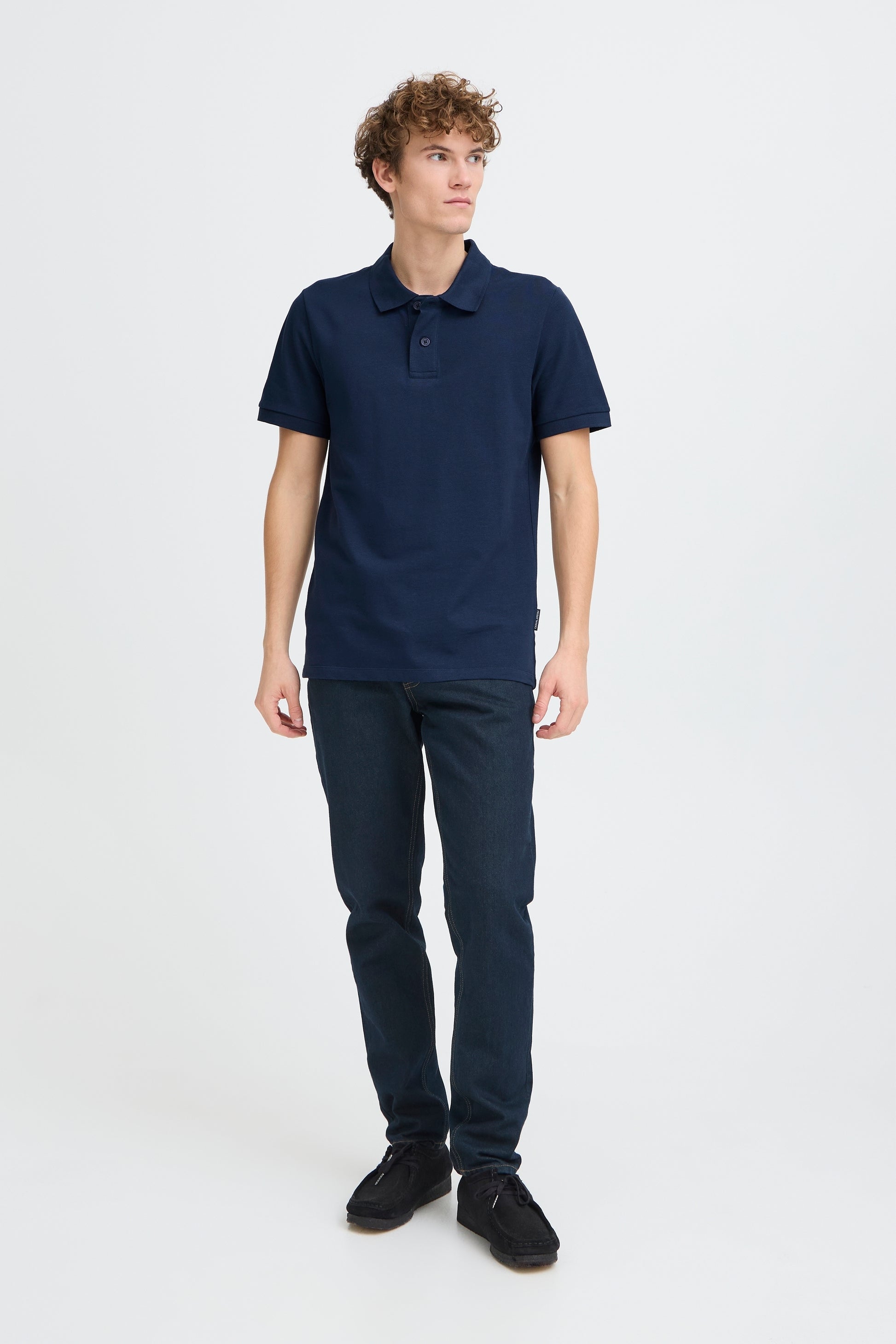Person wearing a navy polo shirt and pants on a white background