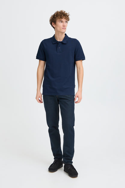Person wearing a navy polo shirt and pants on a white background