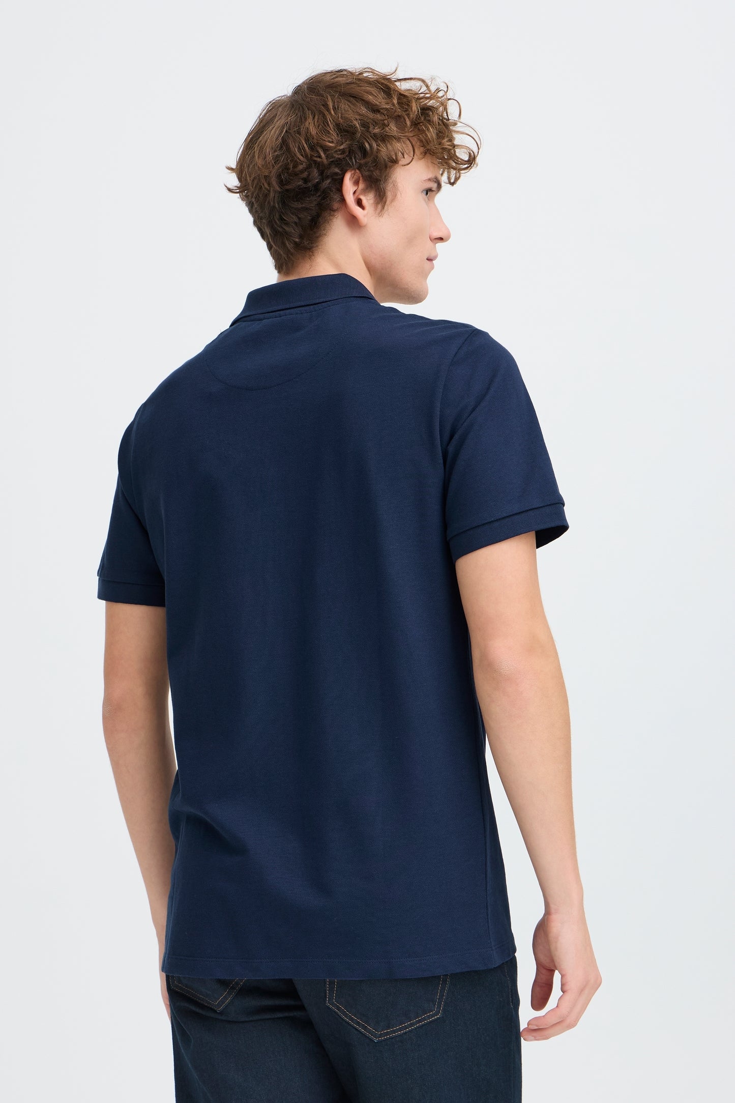 Person wearing a navy blue polo shirt on a white background